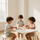 Tres niños juegan con bloques de colores en una pequeña mesa blanca en una habitación luminosa.