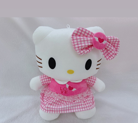 Muñeca de peluche de Hello Kitty con un vestido de cuadros vichy rosa con un lazo en forma de corazón sobre un fondo blanco.