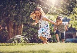 Children playing in a sprinkler on a sunny day.