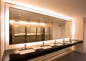 Public restroom with large mirror, sinks, and neutral tones.
