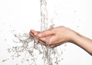 Hand catching water, splashing against a white backdrop.