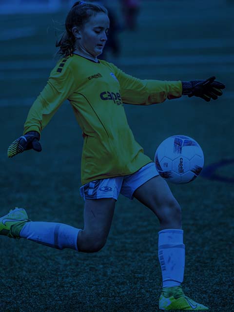 Soccer player in yellow jersey kicks a ball on a grassy field