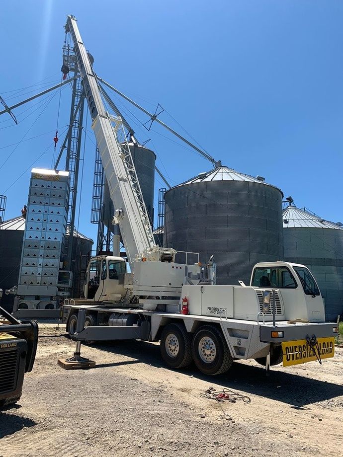 A truck with a crane attached to it is parked in front of a building.