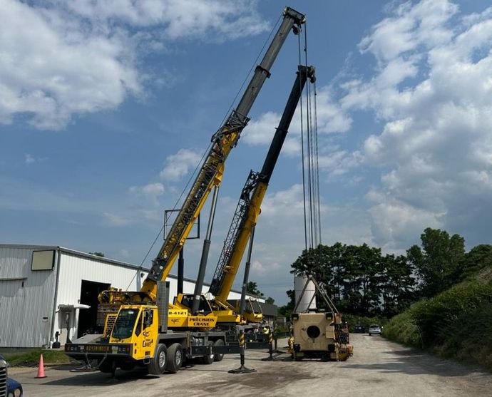 Two crane trucks are parked next to each other in a parking lot
