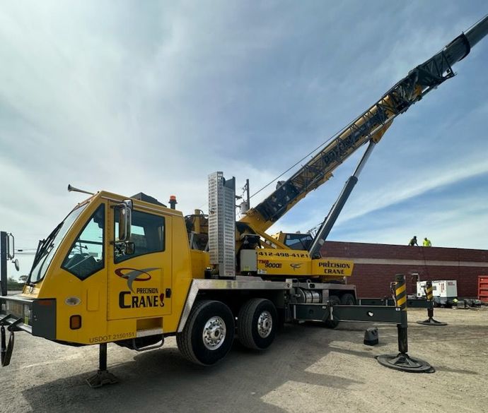 A yellow crane truck is parked in front of a building