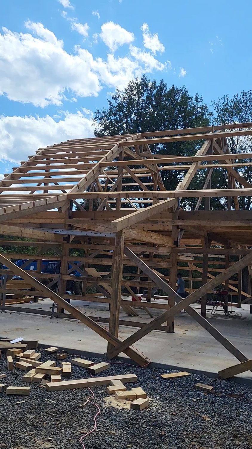 Wooden trusses and roof framing on a house under construction beneath a blue sky