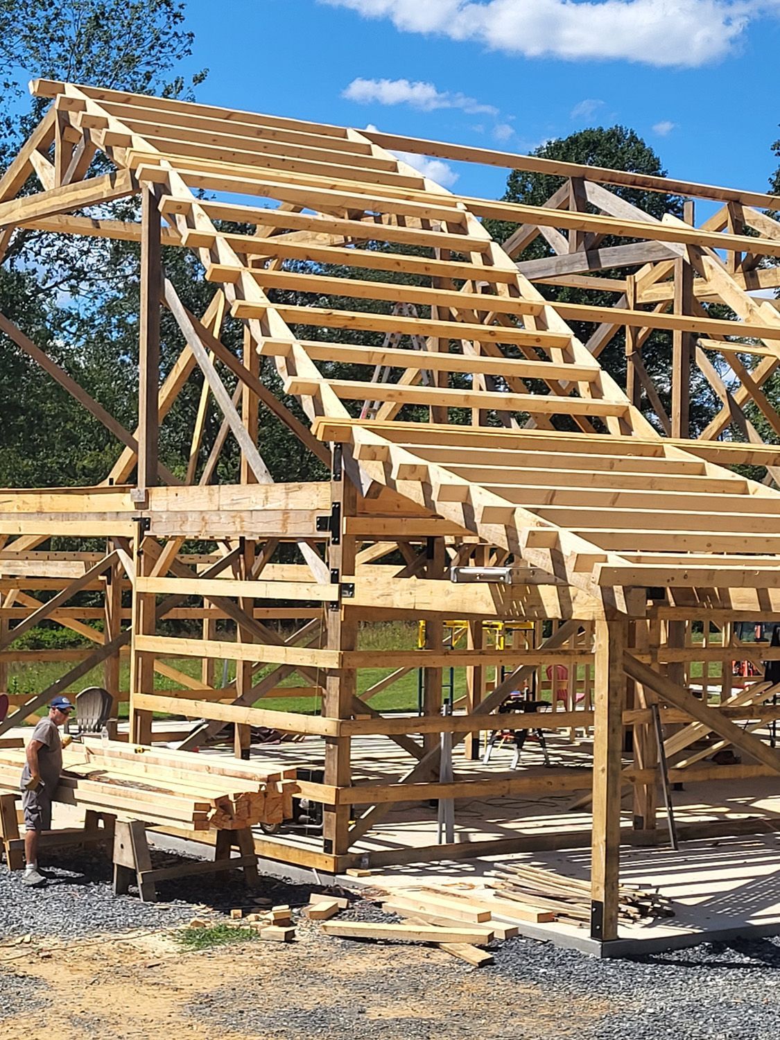Wooden frame of a house under construction with roof trusses and scaffolding in daylight