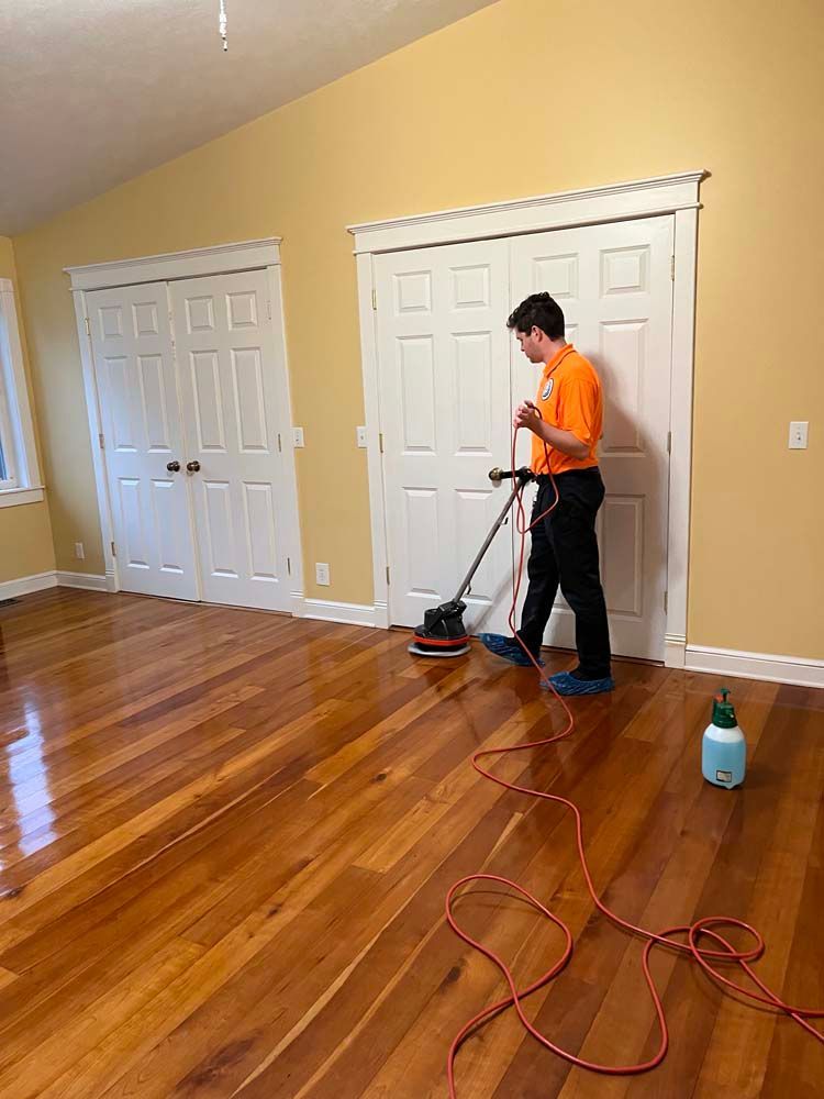 A man is cleaning a hardwood floor with a vacuum cleaner.