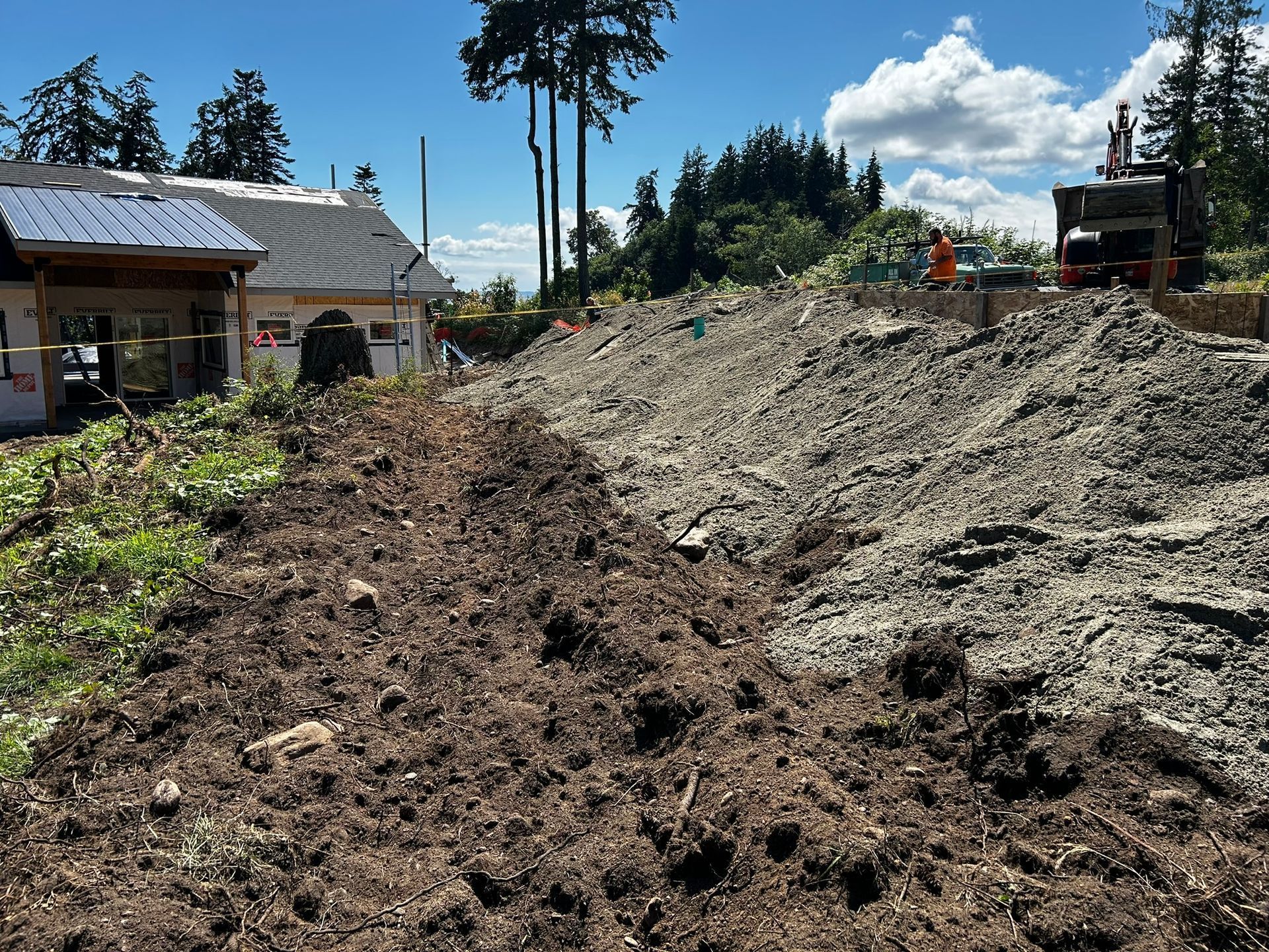 Construction site with large piles of dirt and a building in the background.