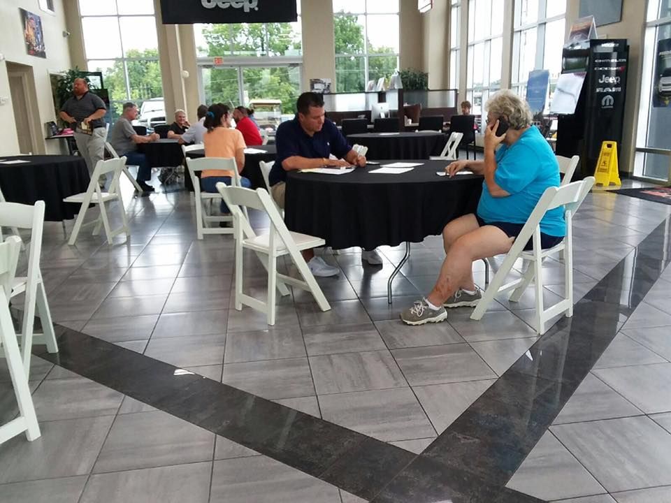 People seated at black round tables in a bright indoor lobby or café area