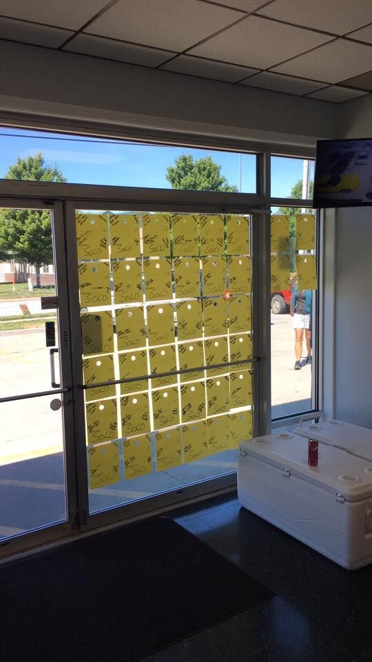 Yellow paper-covered window in a storefront entrance, with street visible outside and a white cooler nearby