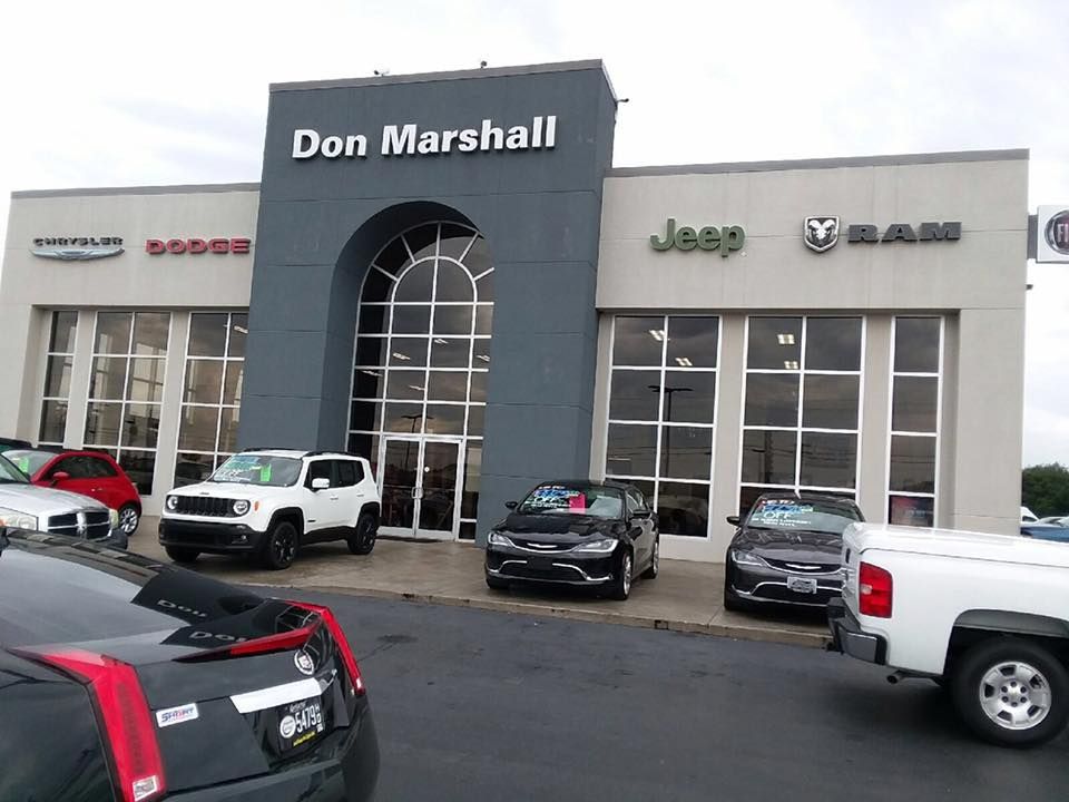 Car dealership exterior with several parked vehicles and a central Don Marshall sign.