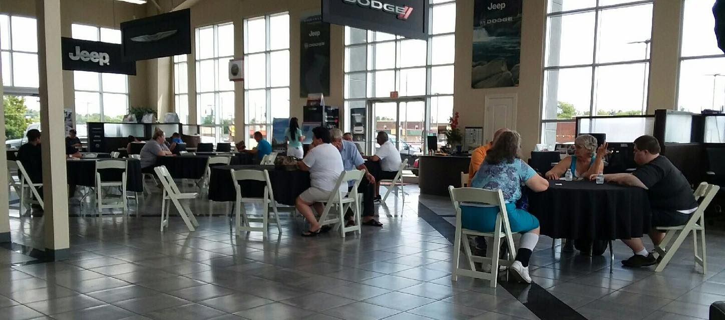Busy airport lounge with travelers seated at tables and large windows in the background