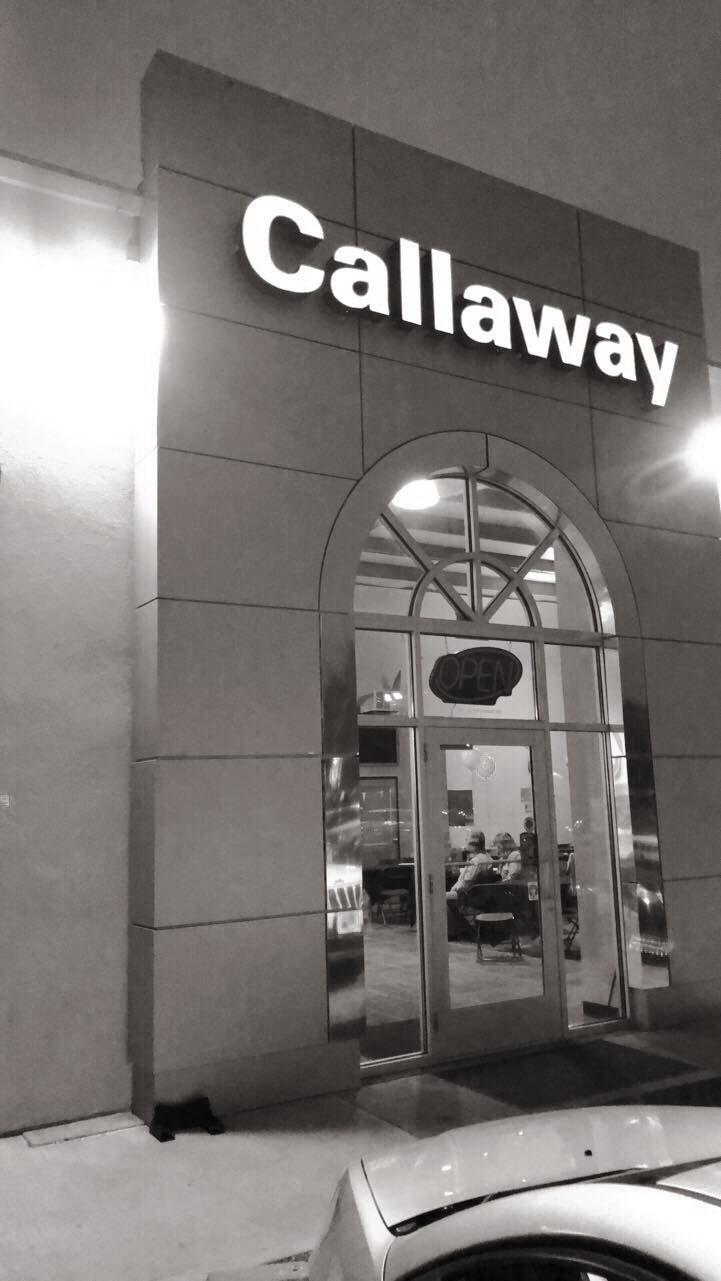Nighttime storefront of Callaway golf shop with illuminated sign and arched glass entrance
