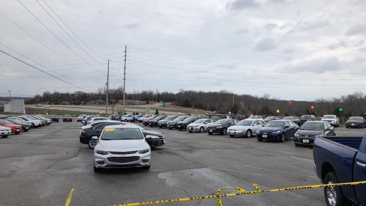Snowy parking lot filled with cars under a cloudy sky, with a silver car centered in front.