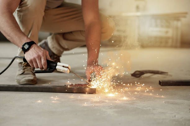 A man is cutting a piece of metal with a grinder.