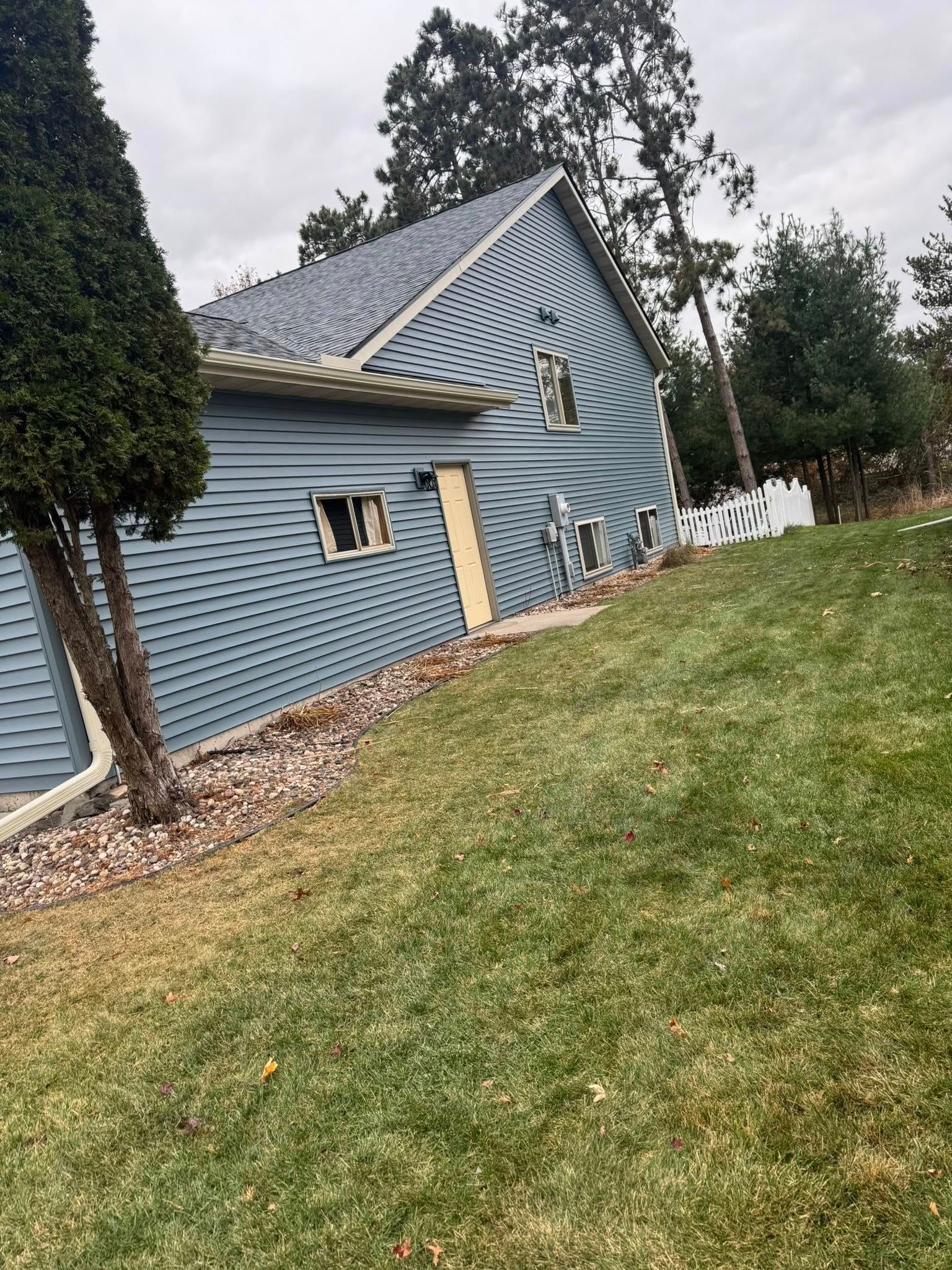 A blue building exterior with distorted, wavy siding, viewed at an angle next to a green lawn and trees.