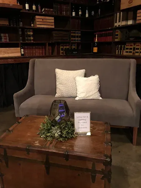 A couch is sitting on top of a wooden trunk next to a table.