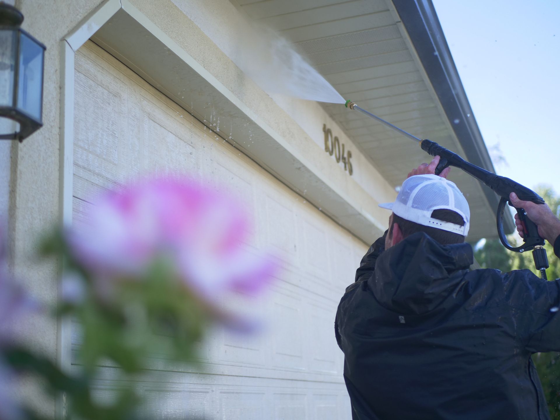 A person pressure washing a house. Building exterior with numbers 
