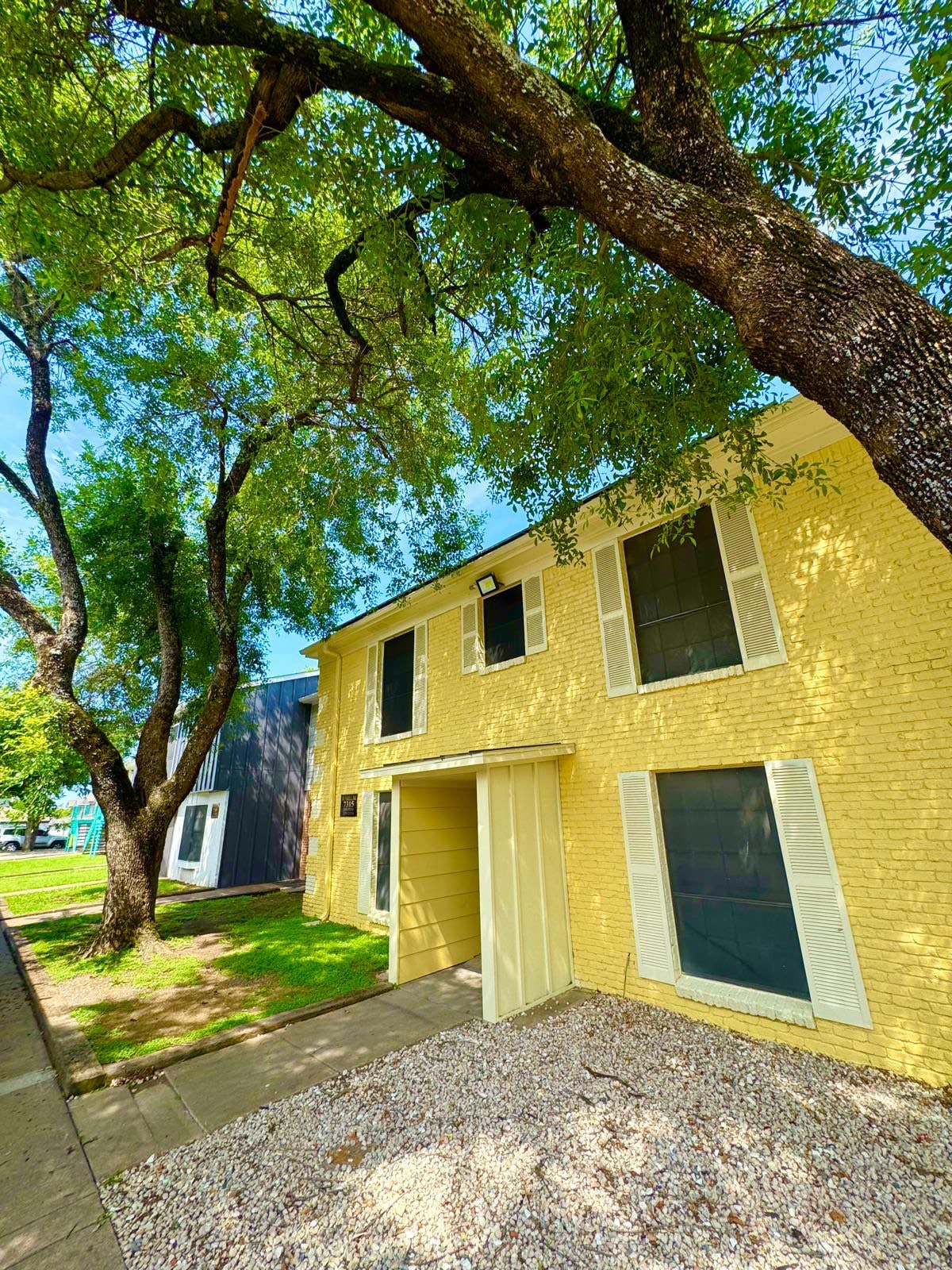 A yellow house with a tree in front of it.