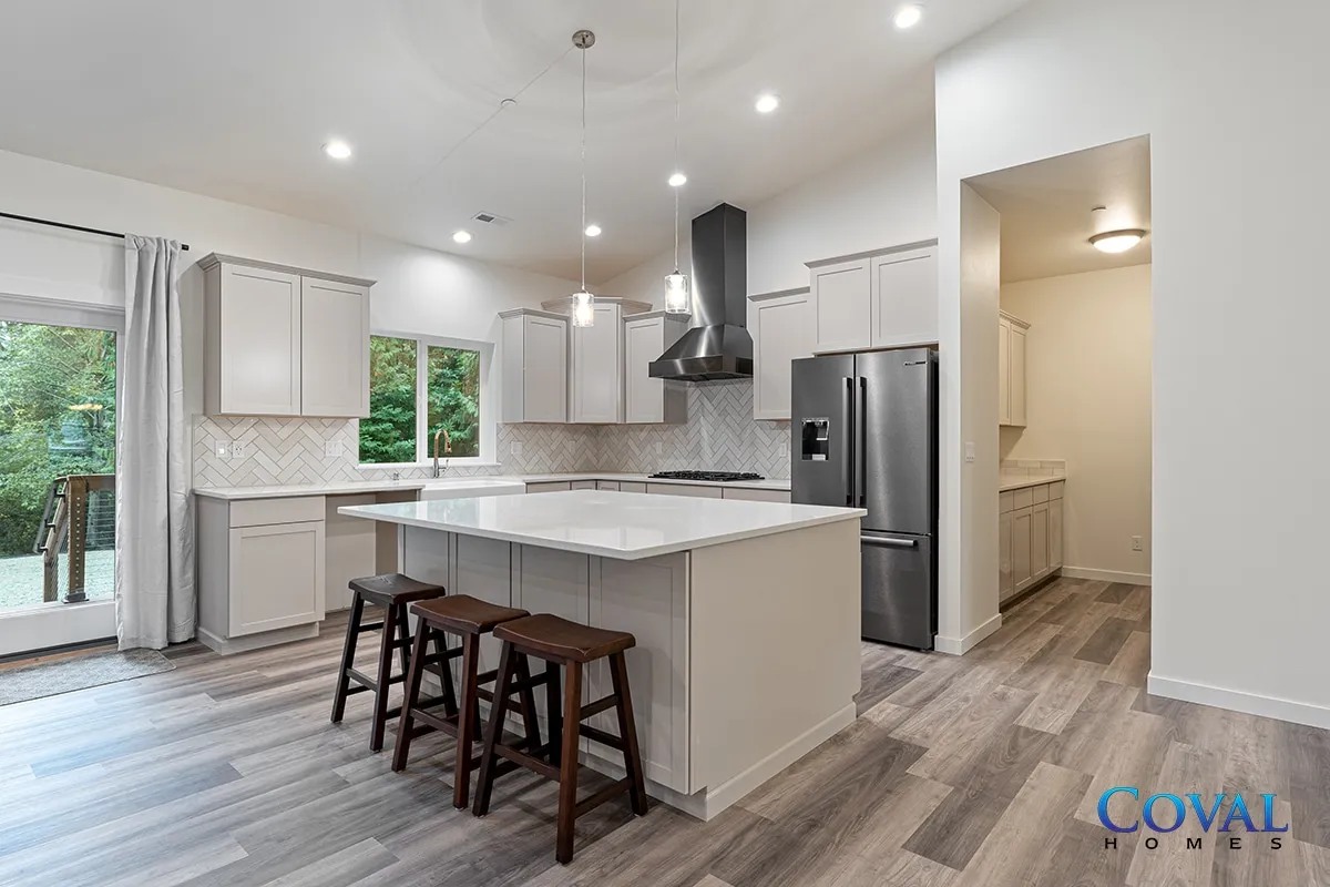 Bright modern kitchen with white cabinets, island seating, stainless fridge, and sliding glass door