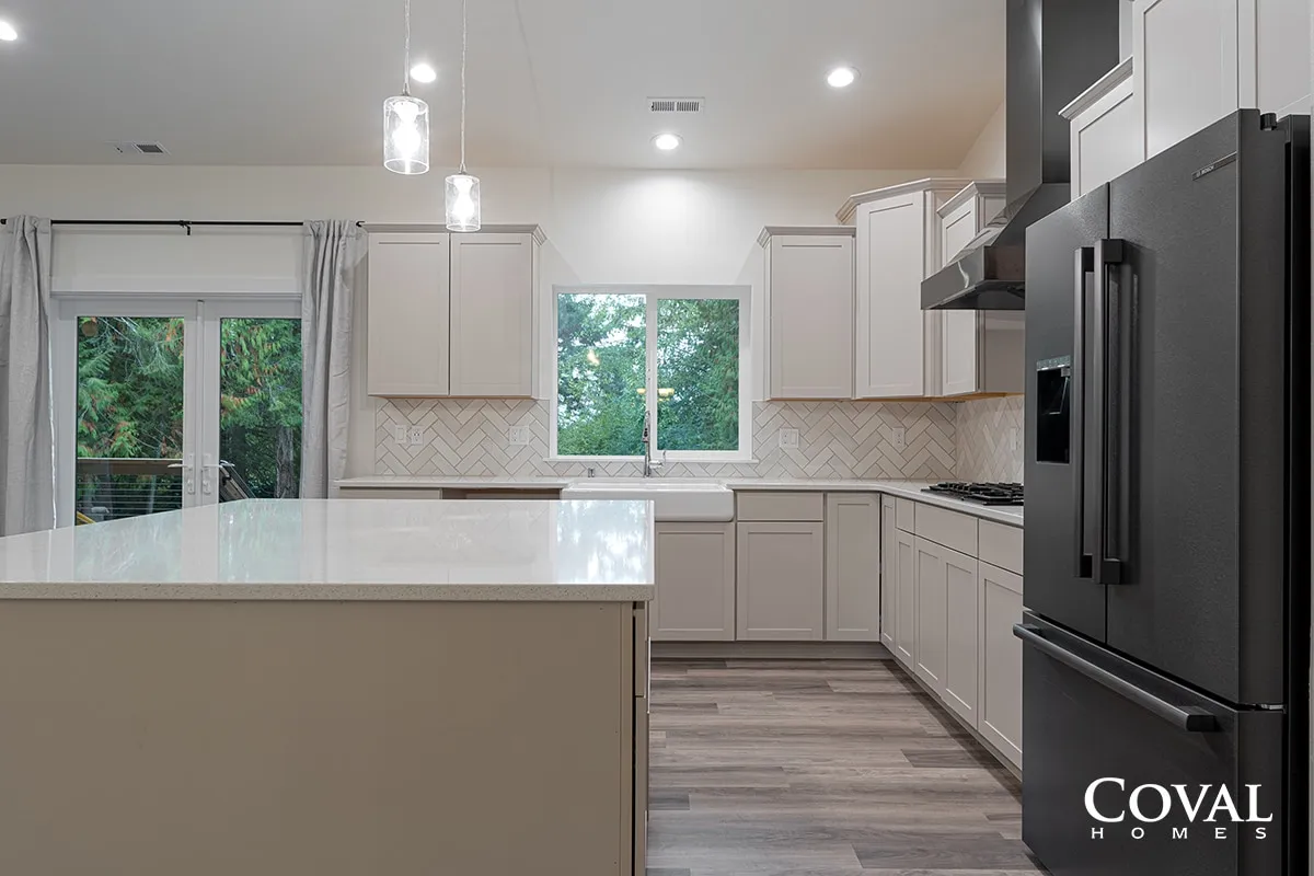 Bright modern kitchen with white cabinets, large island, stainless appliances, and wood-look flooring