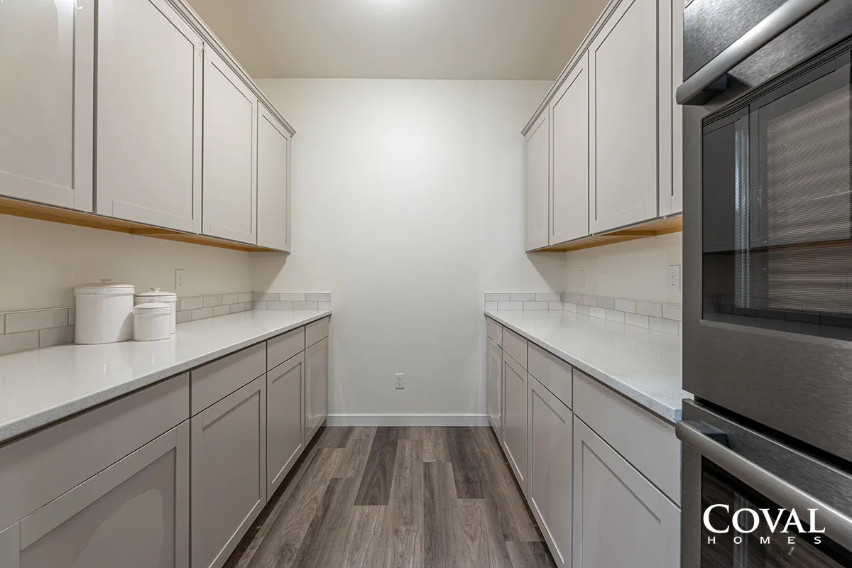 Narrow modern laundry room with white cabinets, countertops, and a front-load washer and dryer.