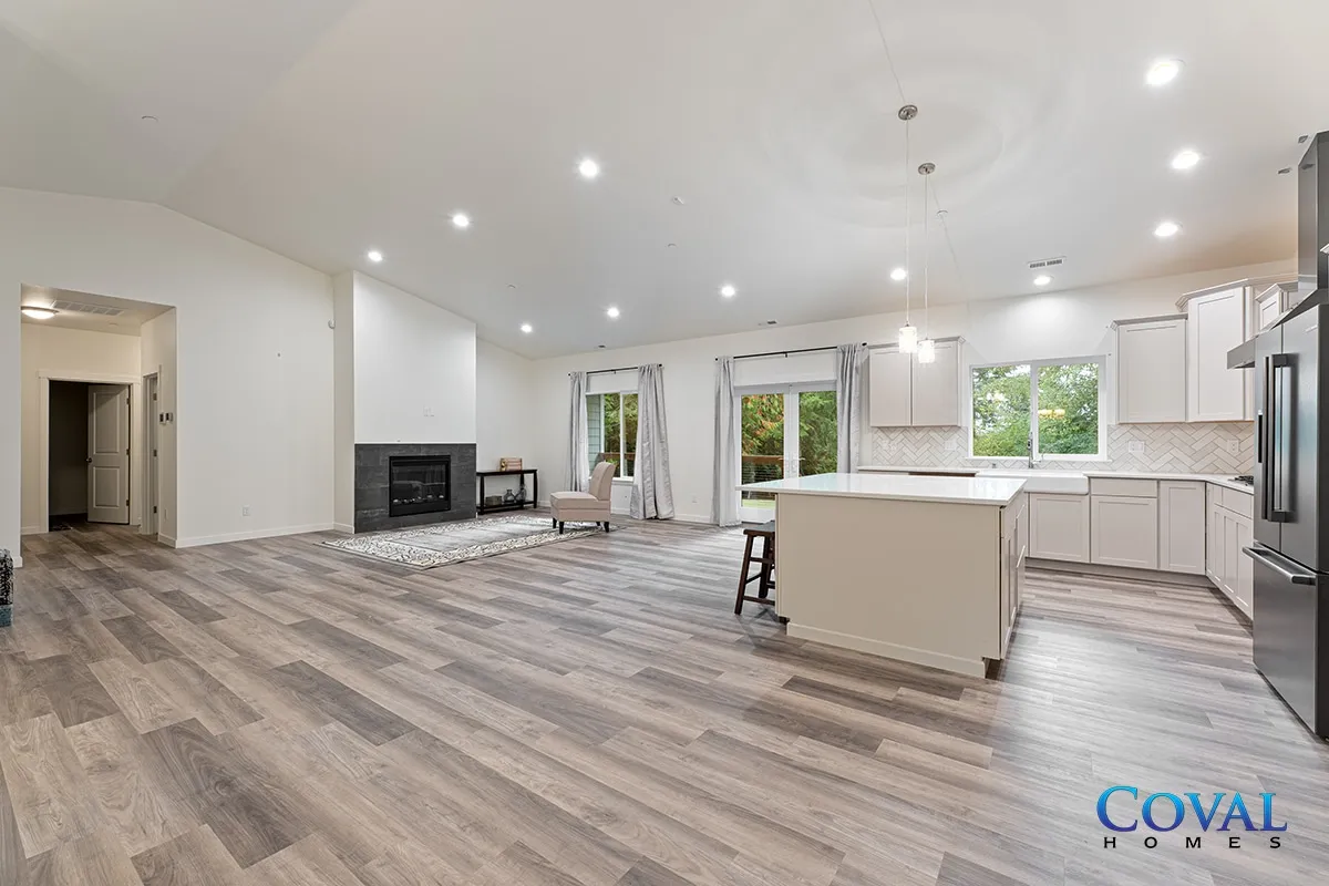 Spacious open-concept living room and kitchen with light wood floors, white cabinets, and fireplace