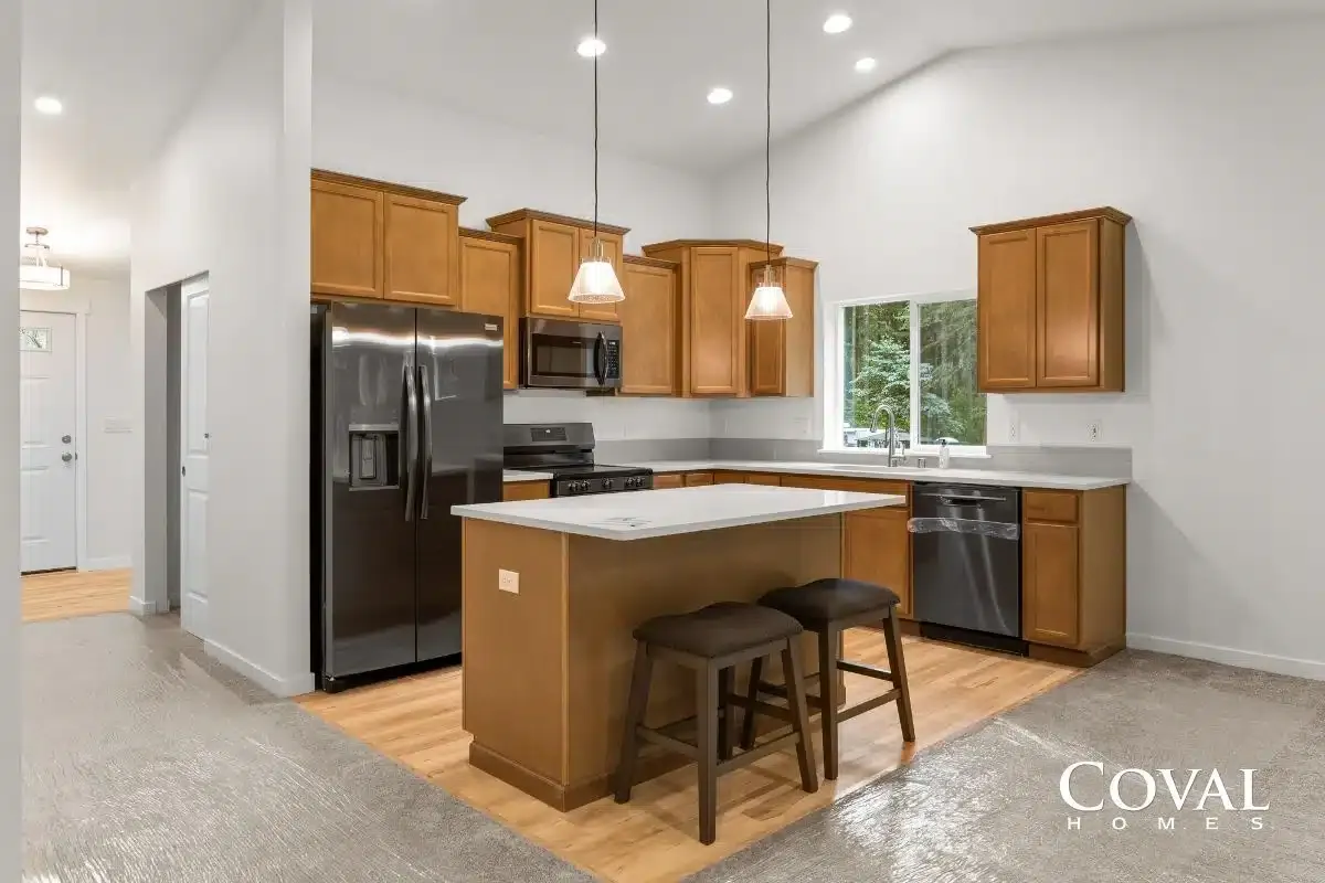 Open kitchen with wood cabinets, stainless appliances, center island, and two stools in a bright home interior