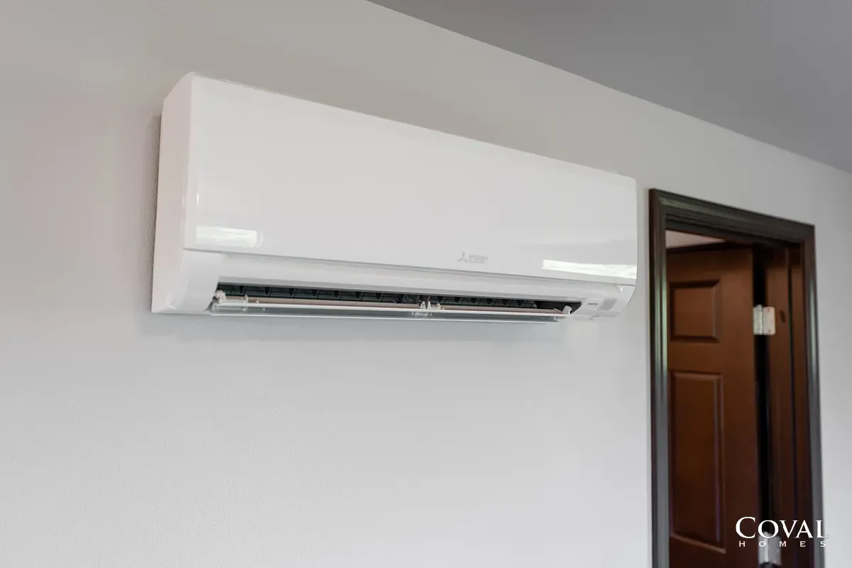 White wall-mounted split air conditioner beside a wooden doorway in a room