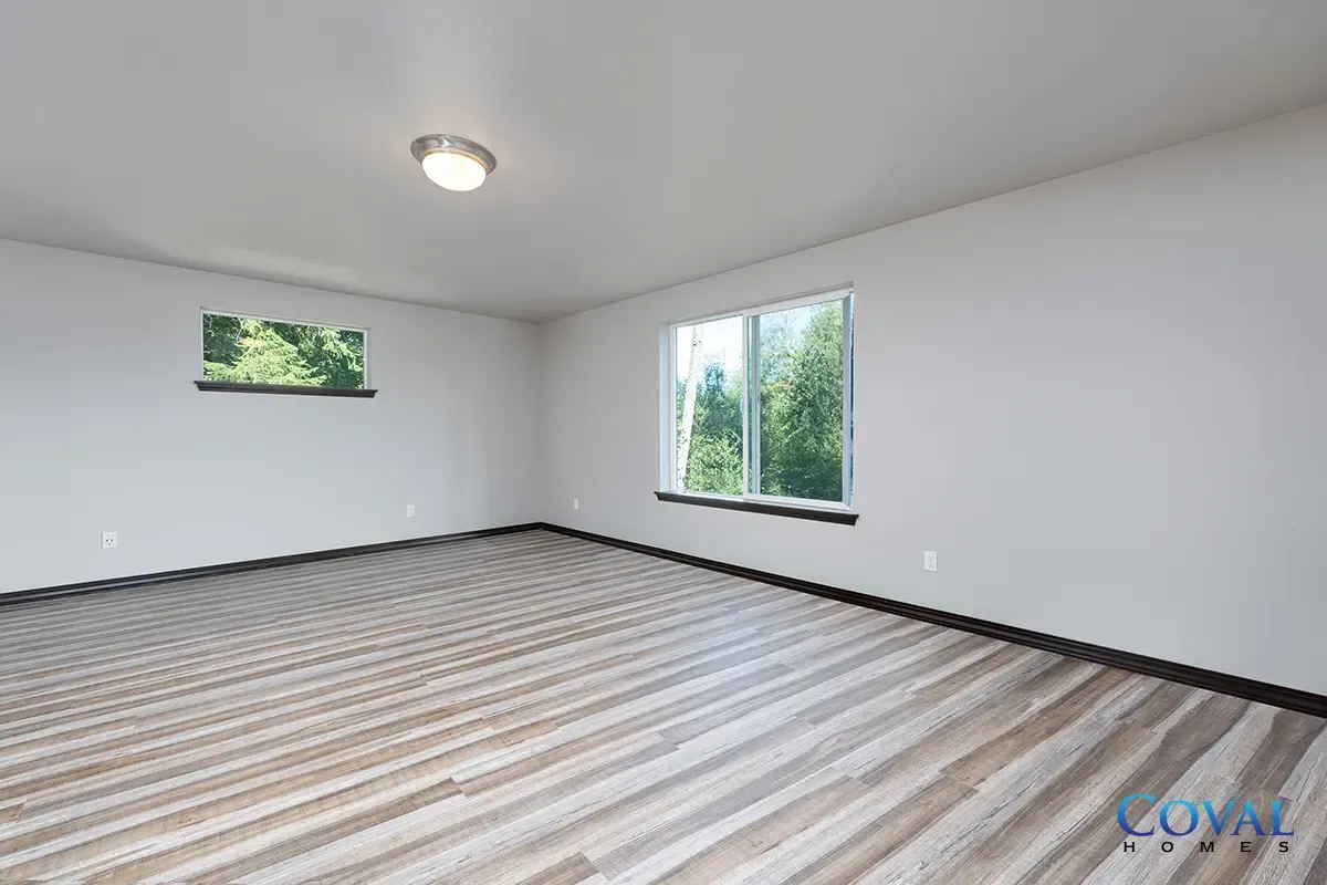 Empty white room with striped carpet, two windows, and ceiling light.