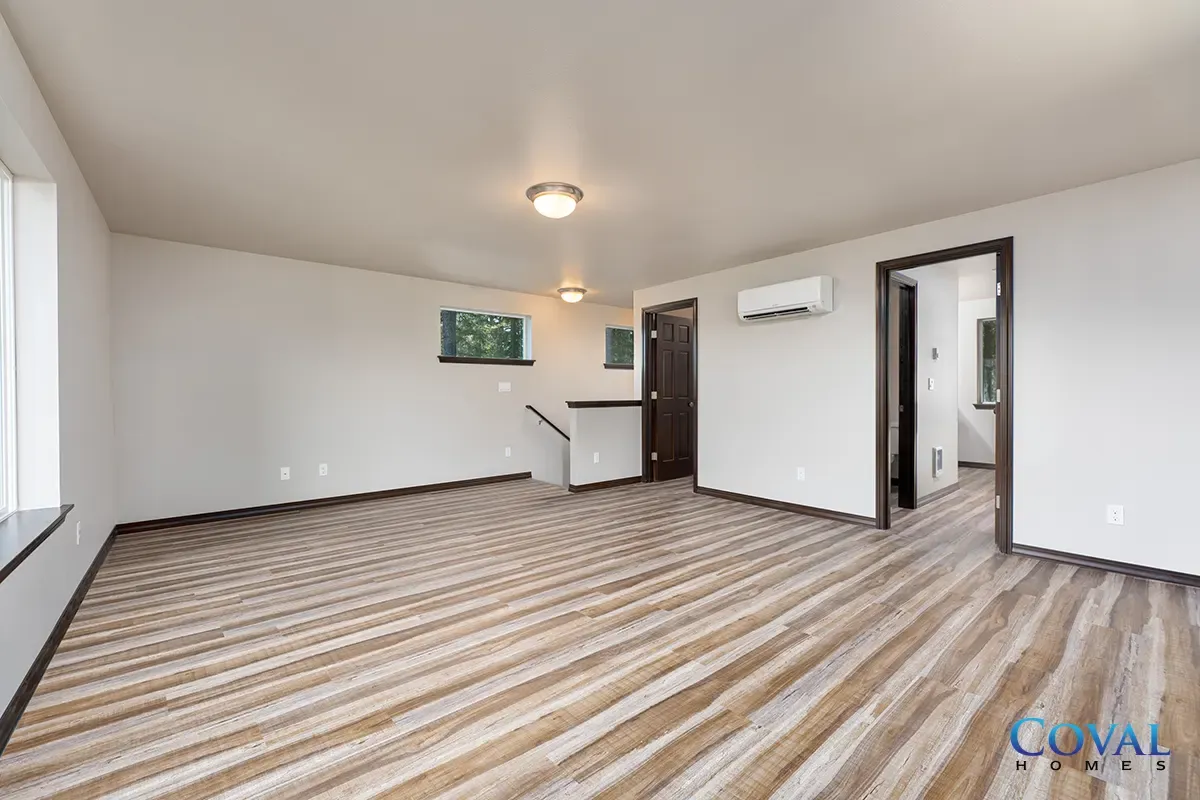 Empty living room with striped carpet, white walls, a small counter, and an open doorway.