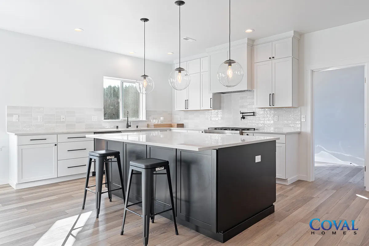 Bright modern kitchen with white cabinets, black island, bar stools, and wood floors