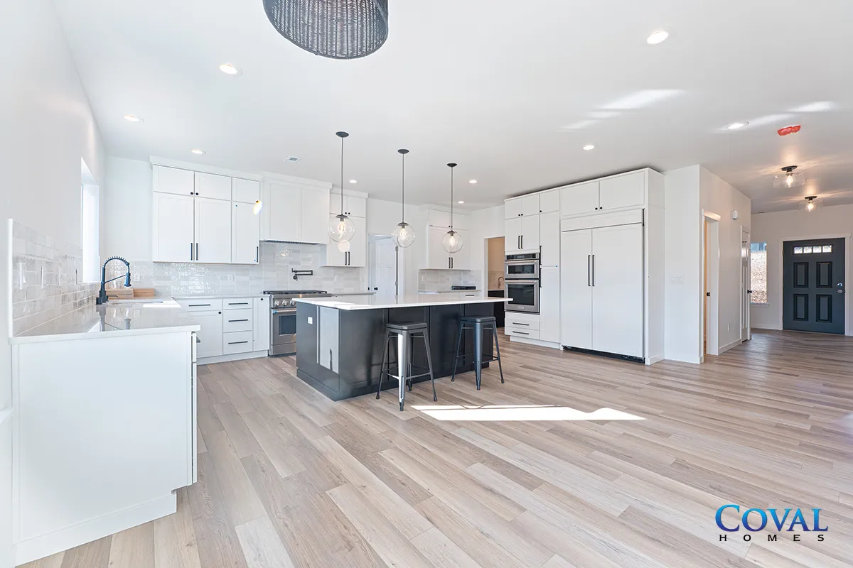 Bright modern open-plan kitchen and living area with white cabinets, dark island, and light wood floors