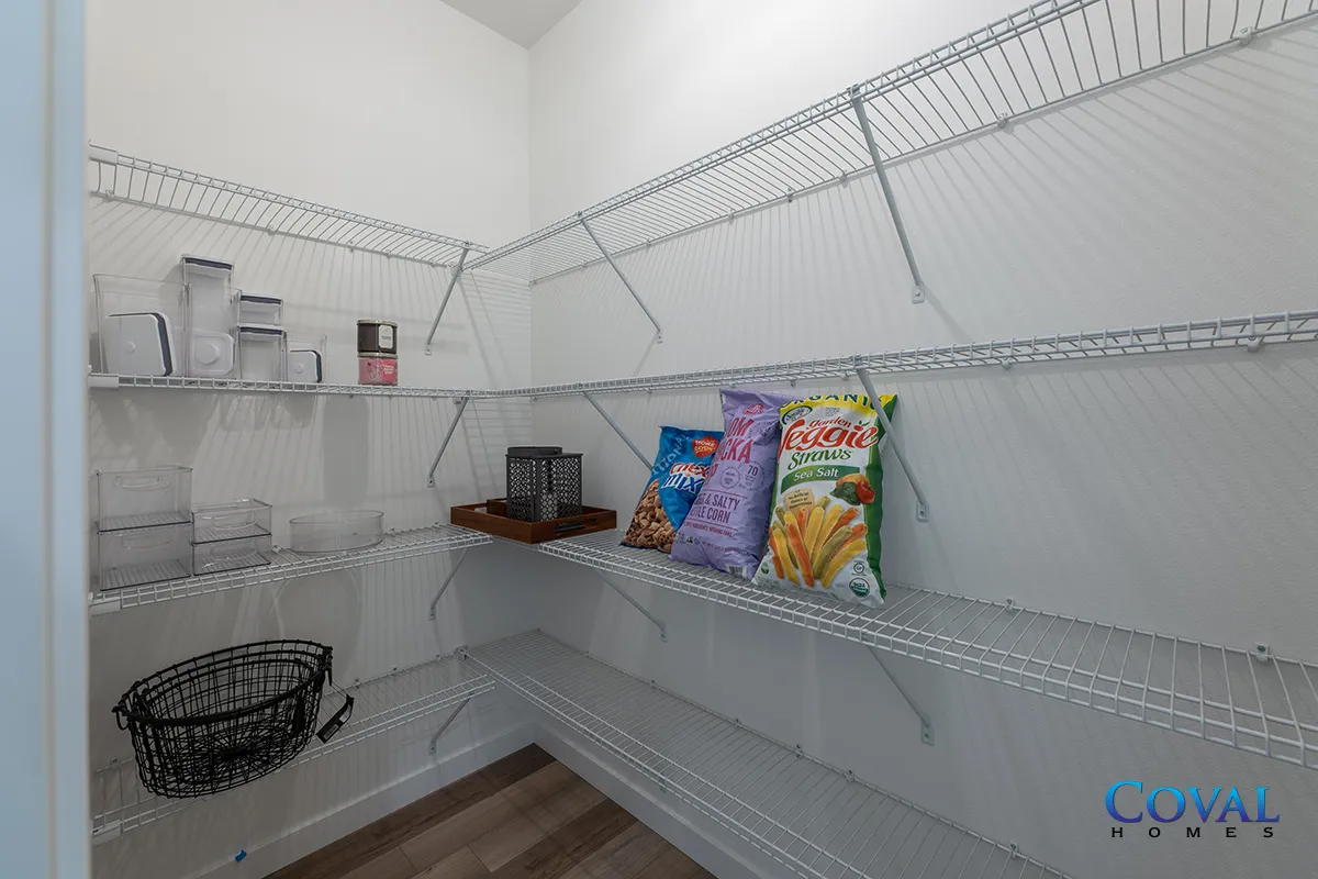 Empty white pantry with wire shelving, a few snacks, bins, and jars on the shelves and floor.
