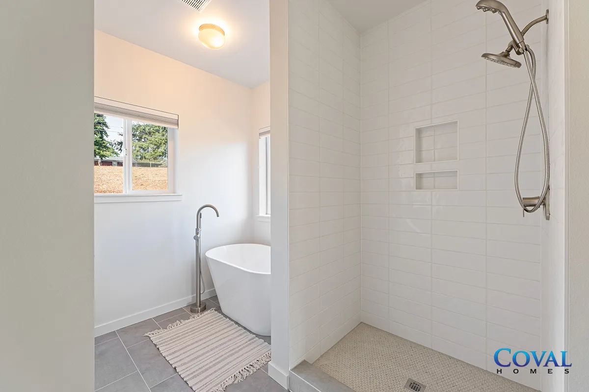 Bright white bathroom with freestanding tub, shower, window, and light gray tile floor
