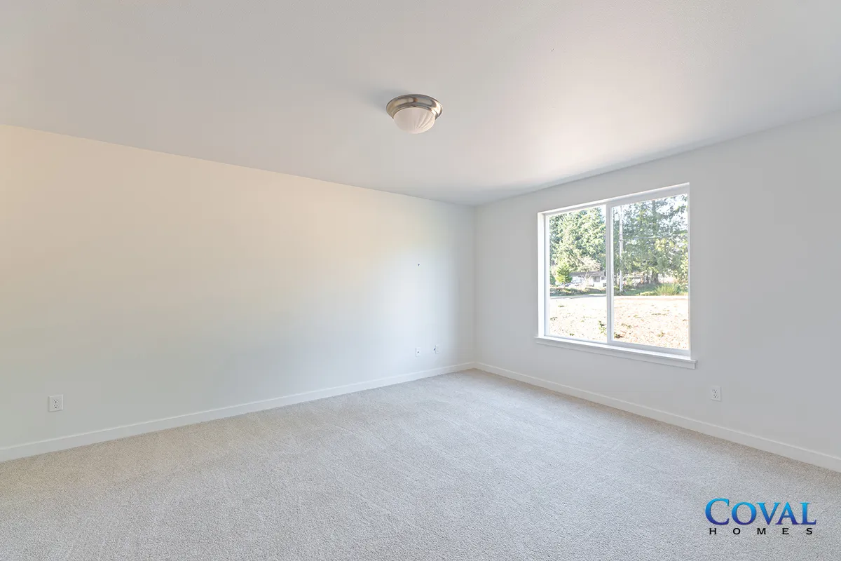 Empty white carpeted bedroom with a window and ceiling light.