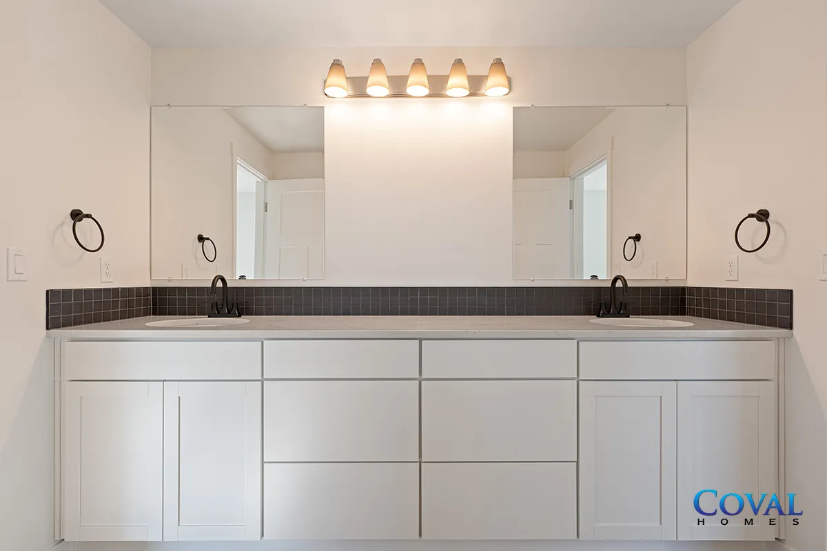 Modern white bathroom vanity with double sinks, large mirror, and wall sconces