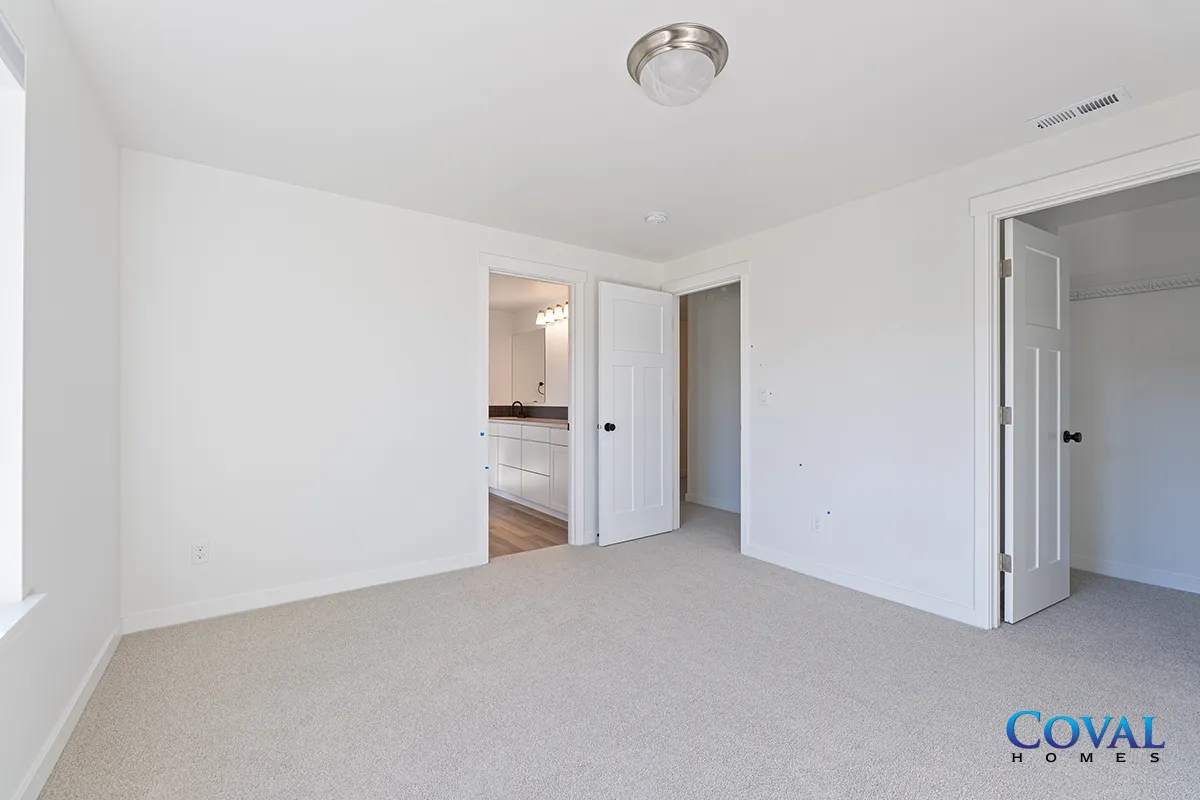 Empty white bedroom with carpet, closet, and open doorway to hallway