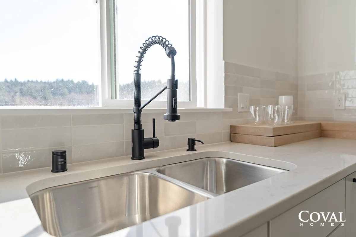 Bright kitchen sink with matte black faucet beside a window and countertop accessories