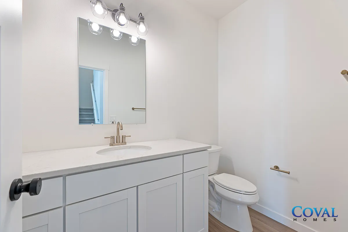 Bright white bathroom with vanity, mirror, light fixture, and toilet