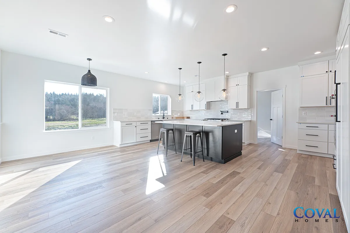 Bright modern open kitchen and living area with white cabinets, island, pendant lights, and wood floors.