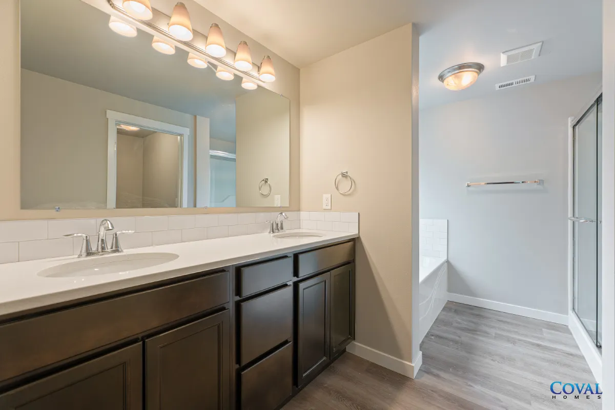 Modern bathroom vanity with dark cabinets, large mirror, and white countertop in a bright hallway.