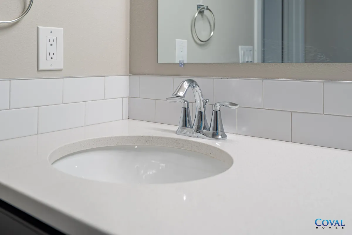Bathroom vanity with white countertop, sink, chrome faucet, and mirror above white tile backsplash