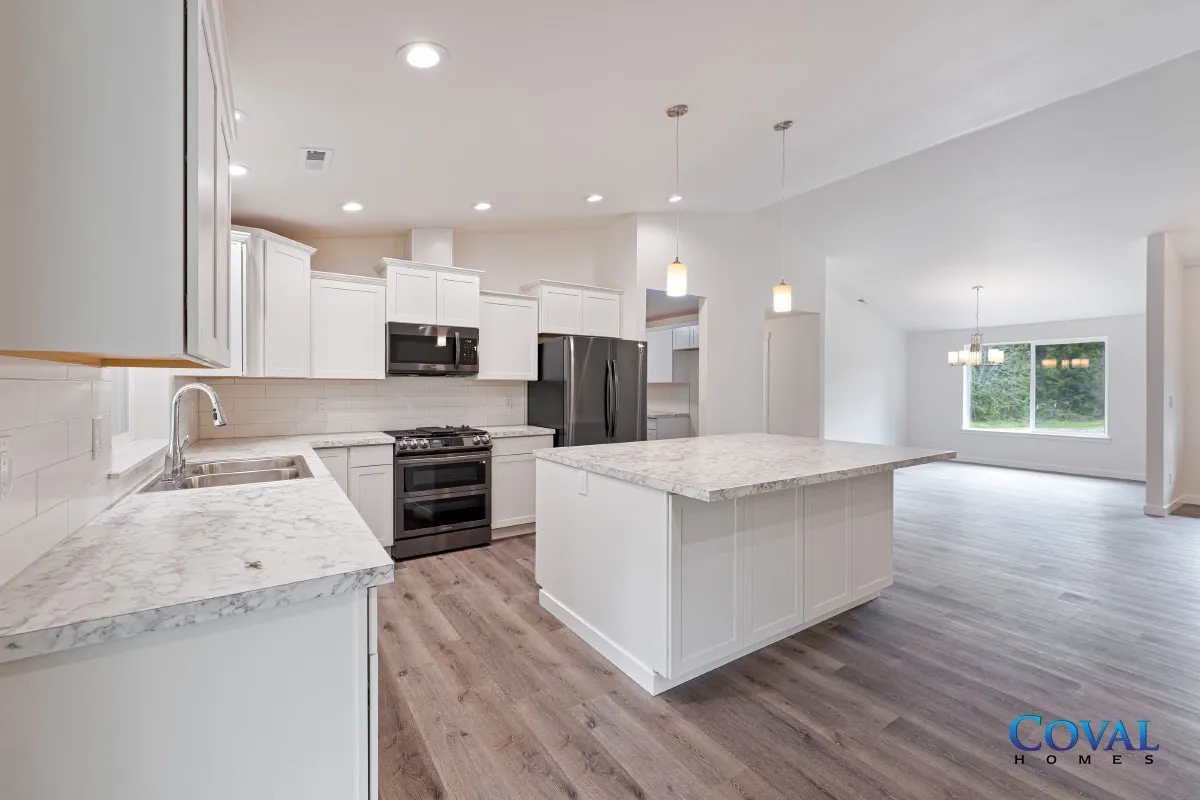 Bright modern kitchen with white cabinets, granite island, and gray wood floors