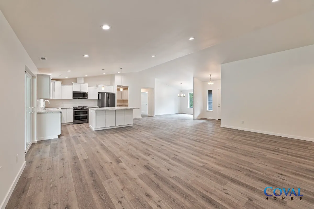 Bright empty open-plan living room and kitchen with light wood floors and white walls