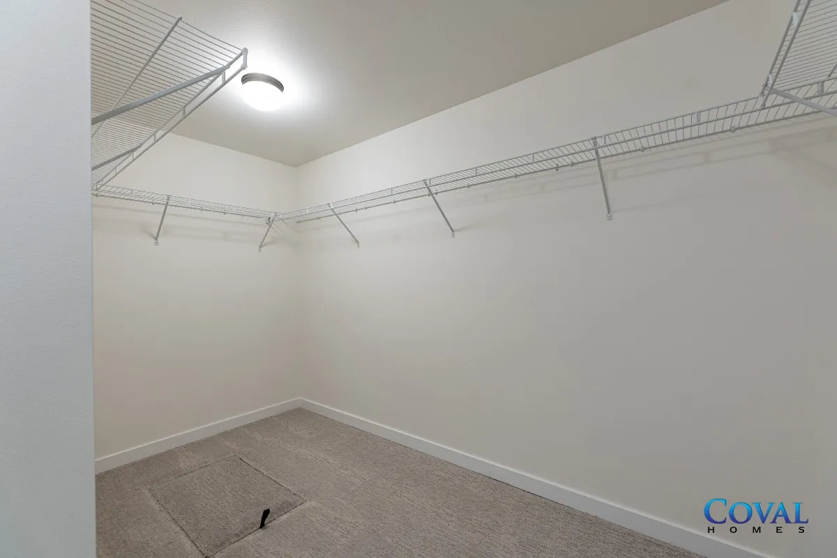 Empty walk-in closet with white wire shelving and beige carpet.