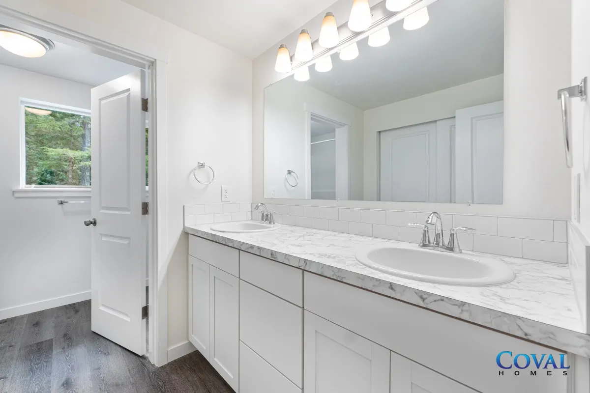 Bright white bathroom vanity with large mirror, double sinks, and a windowed shower area