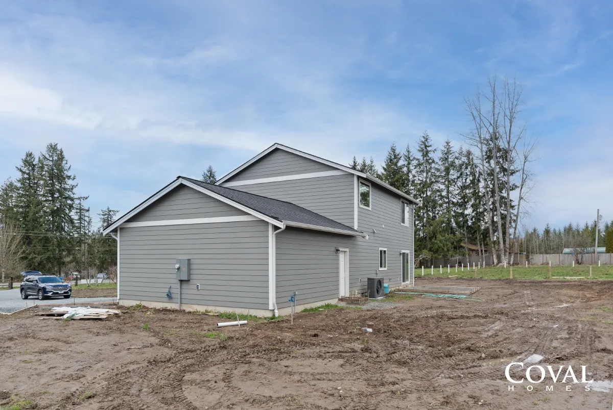 Gray two-story house with attached garage on a cleared lot under a blue sky.