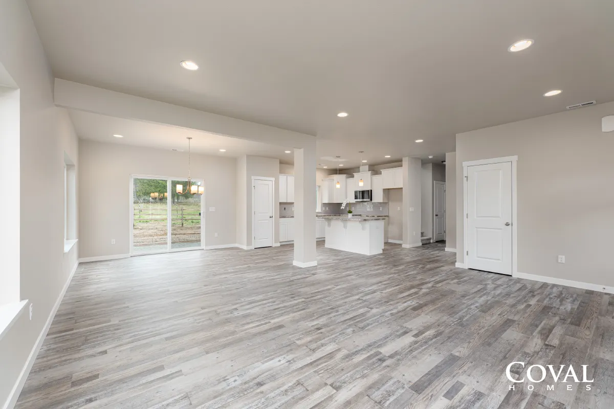 Bright open-concept living room and kitchen with gray wood floors and white walls